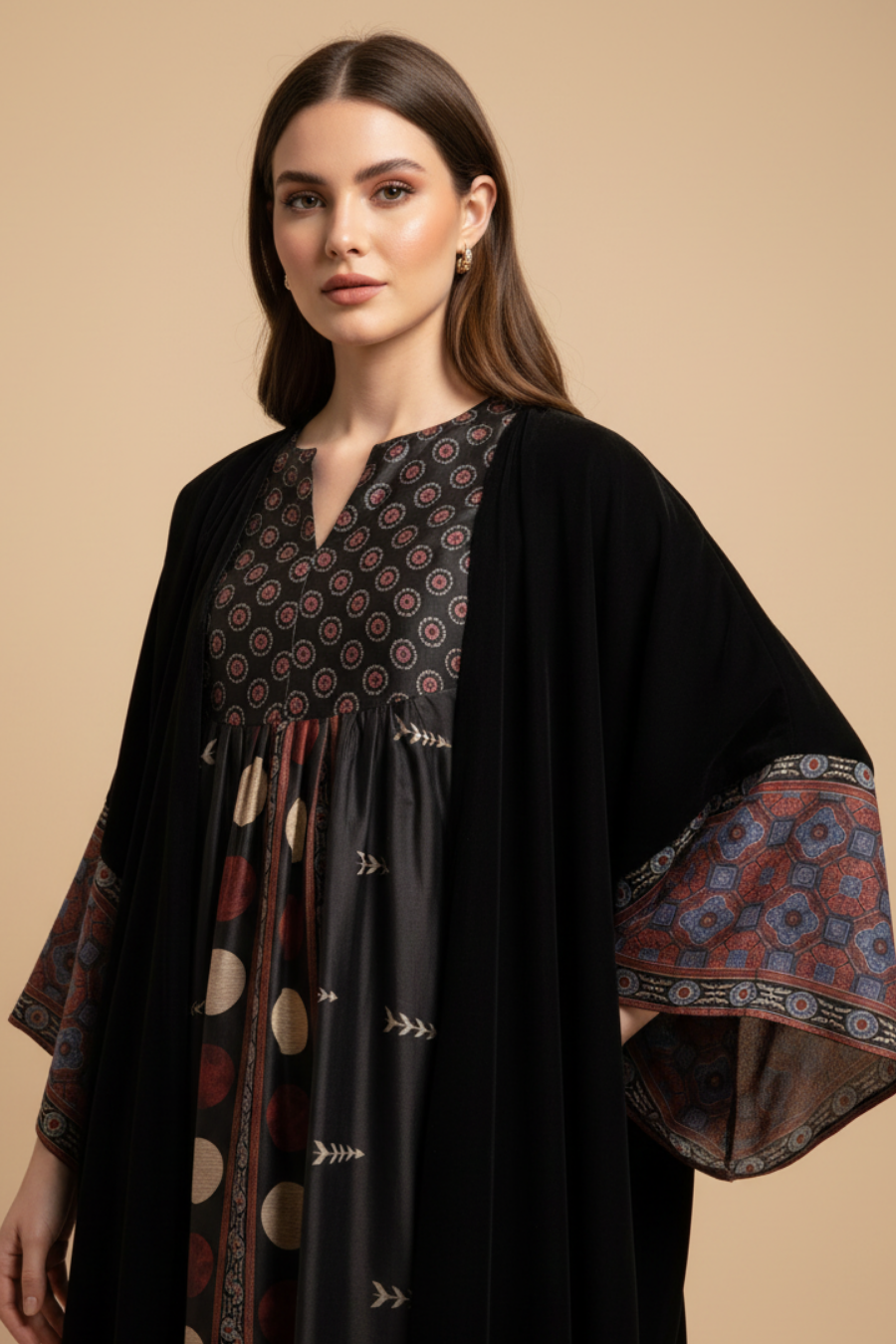 Woman wearing a black abaya with patterned sleeves against a beige background